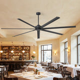 Large black ceiling fan in a restaurant setting with tables and chairs.
