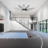 Large black ceiling fan with LED light installed over a modern indoor basketball court