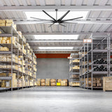 Large black ceiling fan with integrated LED light installed in a warehouse storage area