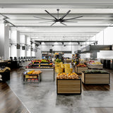 Large black ceiling fan with integrated LED light installed in a modern supermarket
