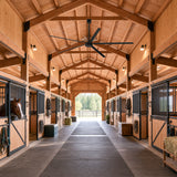 AeroVault 12 FT HVLS industrial ceiling fan with five aluminum blades installed in a large horse stable with individual stalls.