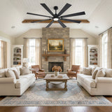 Living room with stone fireplace under Jovora 72-inch large black 8-blade ceiling fan glowing light
